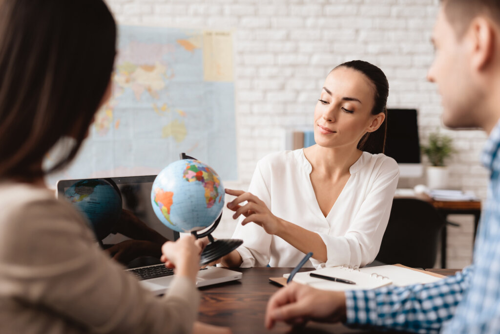 A travel advisor holding a globe while discussing travel plans with her clients.